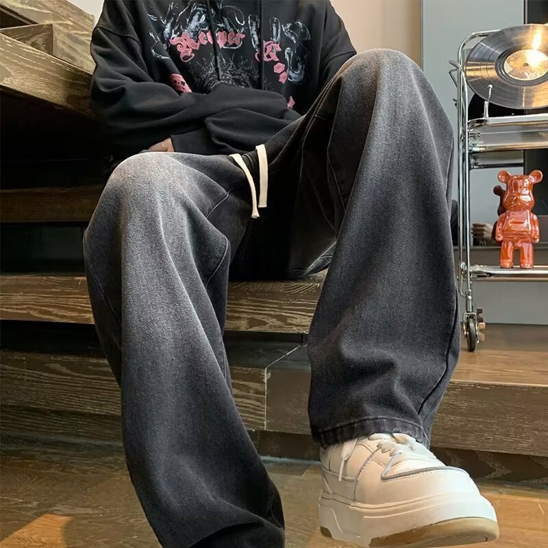 Japanese-style Drawstring Elastic-waist Jeans For Men styled with a black hoodie and white sneakers.